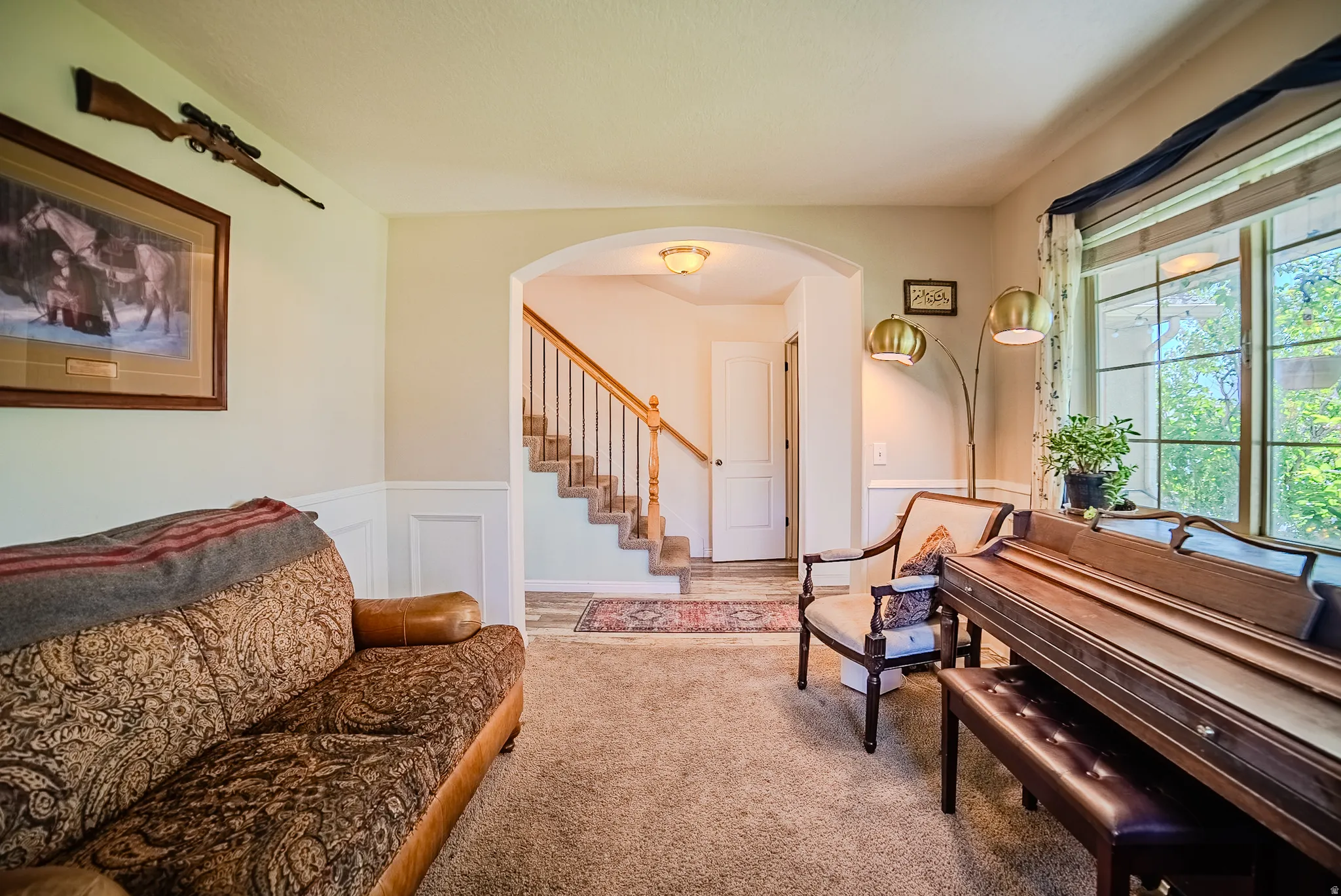 Carpeted living area featuring wainscoting and an arched entry