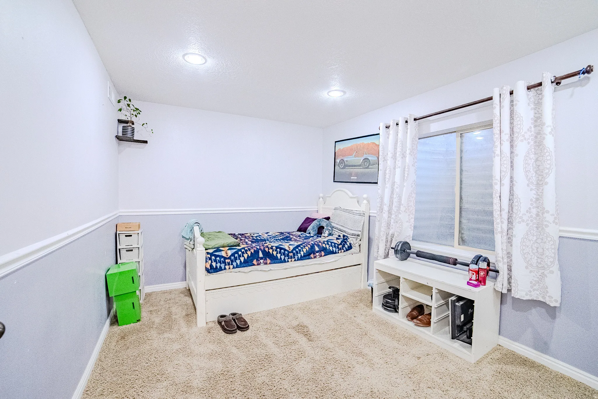 Carpeted room featuring a window with white curtains, recessed lighting, and two-tone wall paint with chair rail molding