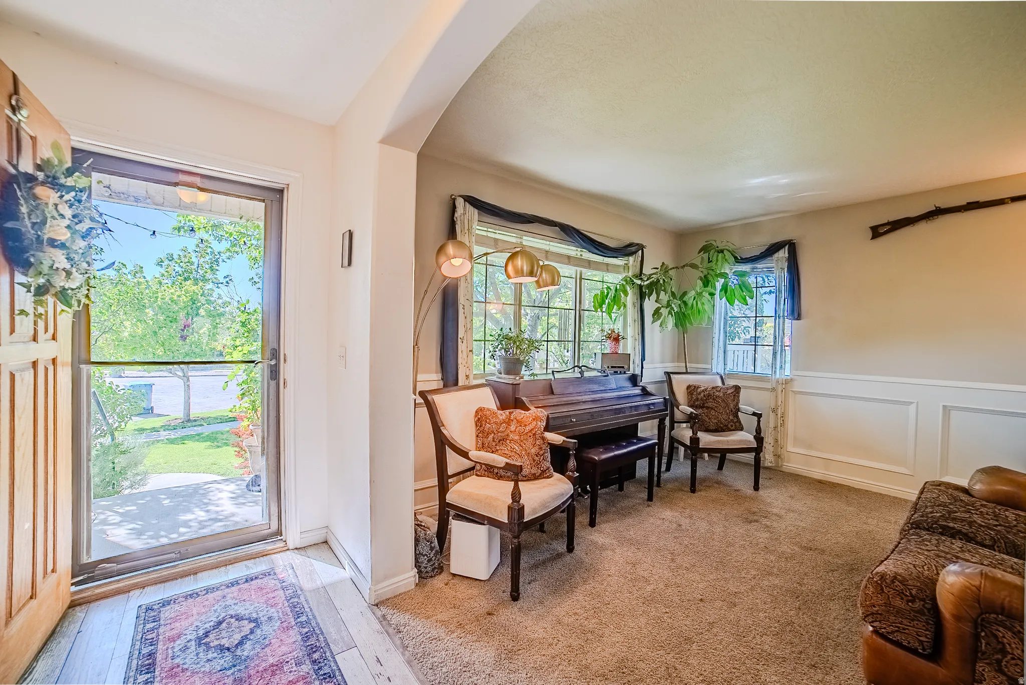 Entryway featuring a wood-panel door with a storm door, opening to a carpeted room