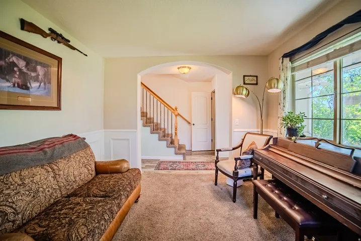 Carpeted living area featuring wainscoting and an arched entry