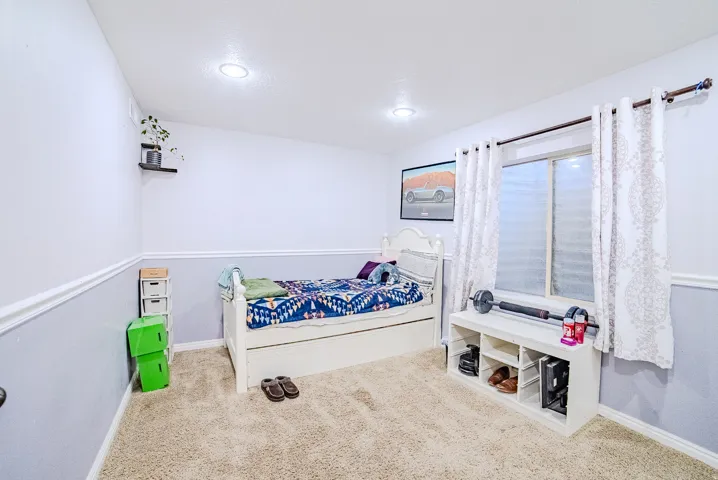 Carpeted room featuring a window with white curtains, recessed lighting, and two-tone wall paint with chair rail molding