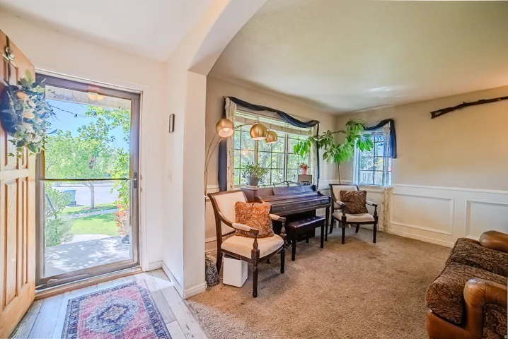 Entryway featuring a wood-panel door with a storm door, opening to a carpeted room