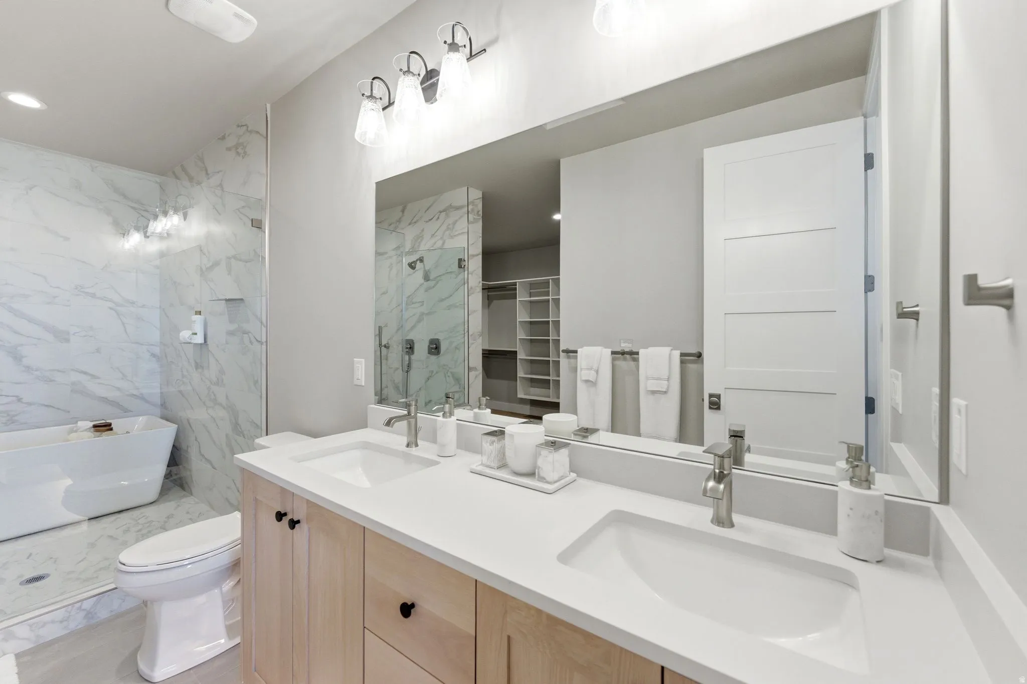 Dual vanity with light wood-finish cabinetry, white countertops, and undermount sinks
