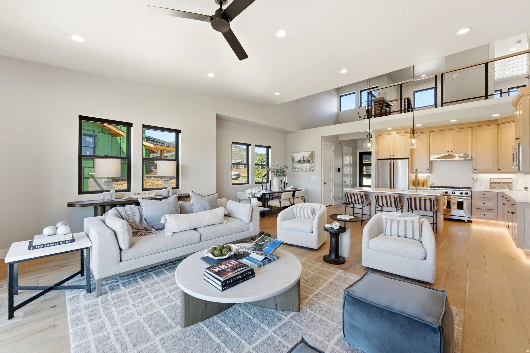 Open-concept living area with high ceilings, recessed lighting, and light wood-finish flooring