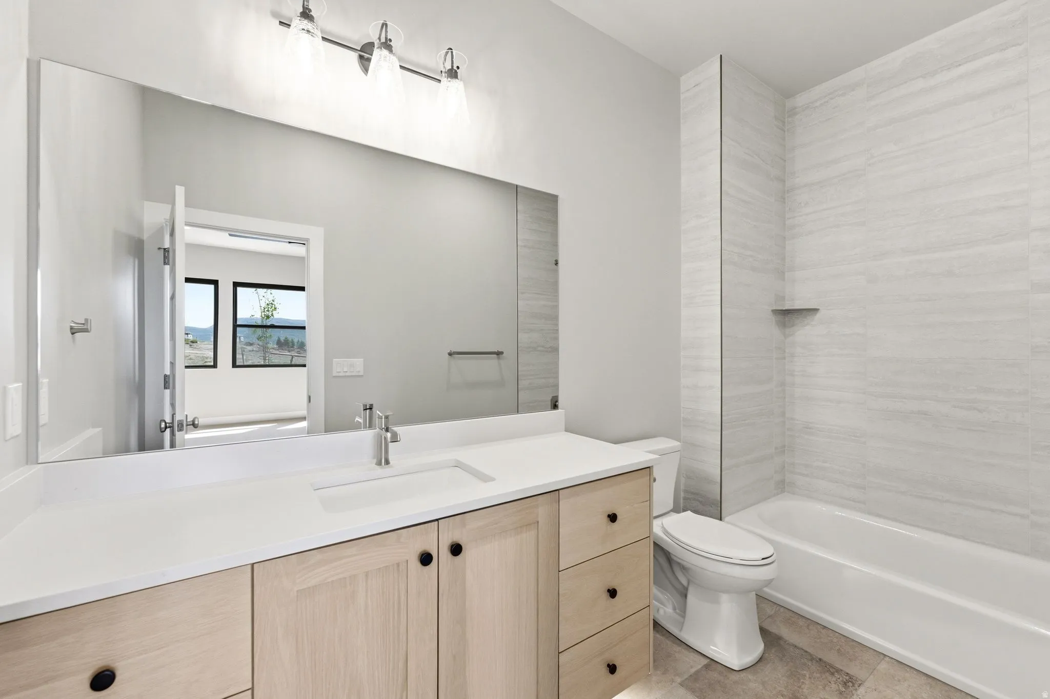 Contemporary bathroom with a light wood-finish vanity, white countertop, and integrated sink
