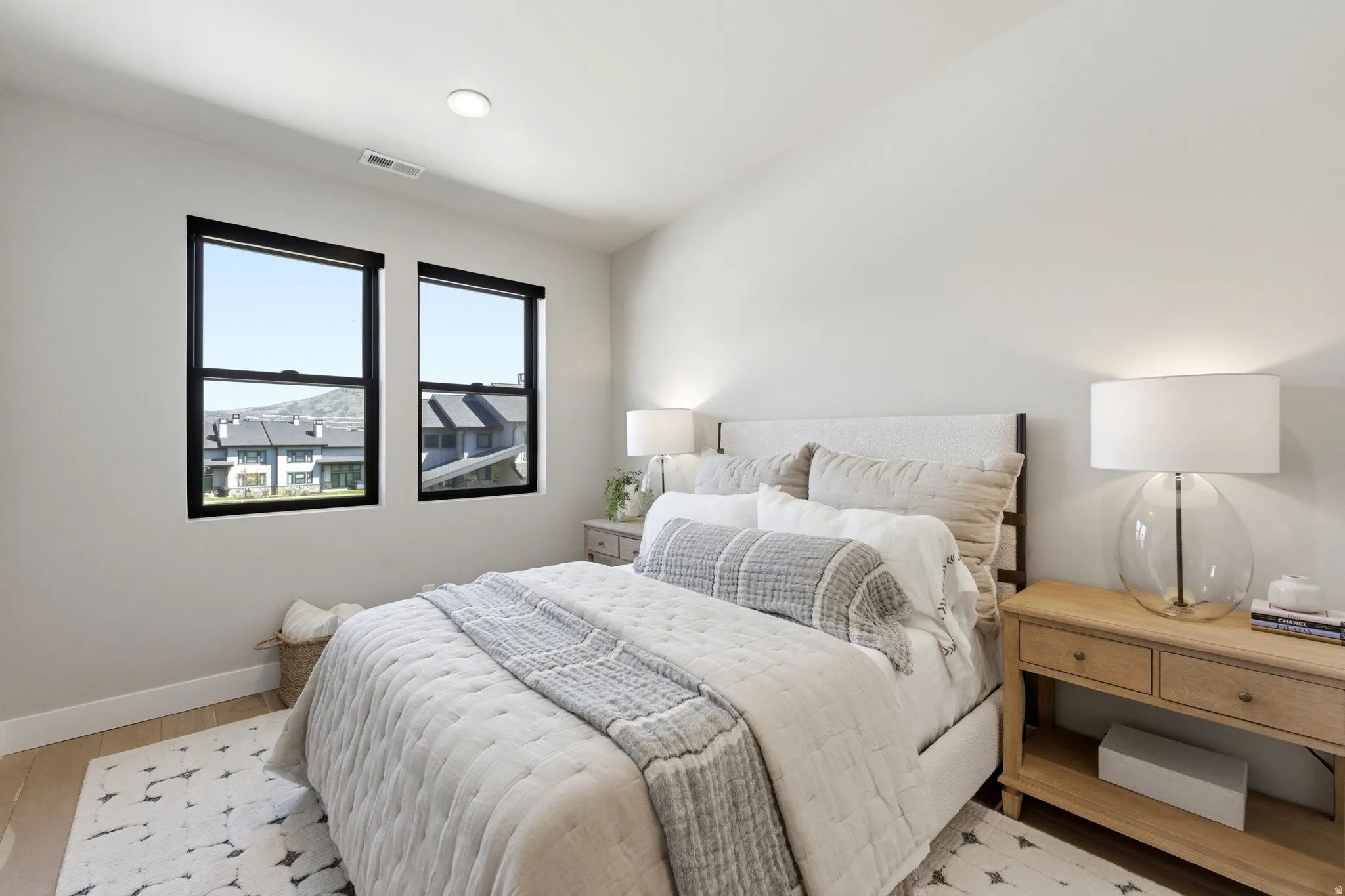 Bright room featuring two large black-framed windows, recessed lighting, wood-finish flooring, and light-toned walls