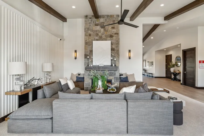 Spacious interior featuring a stone-clad fireplace, built-in bench seating, exposed wood ceiling beams, and a modern ceiling fan
