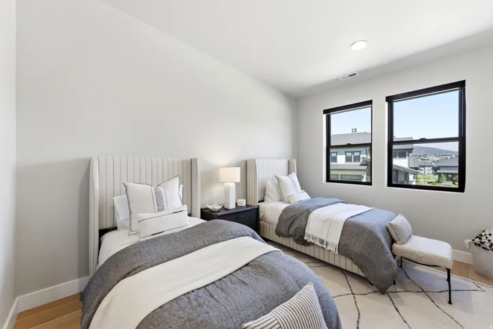 Contemporary room featuring two distinct upholstered wingback beds, recessed lighting, and light wood-finish flooring