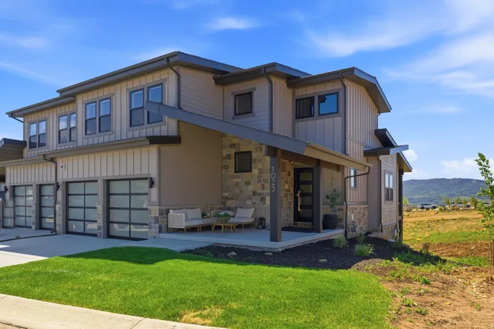 Contemporary multi-level exterior featuring tan siding, stone accents, and dark trim