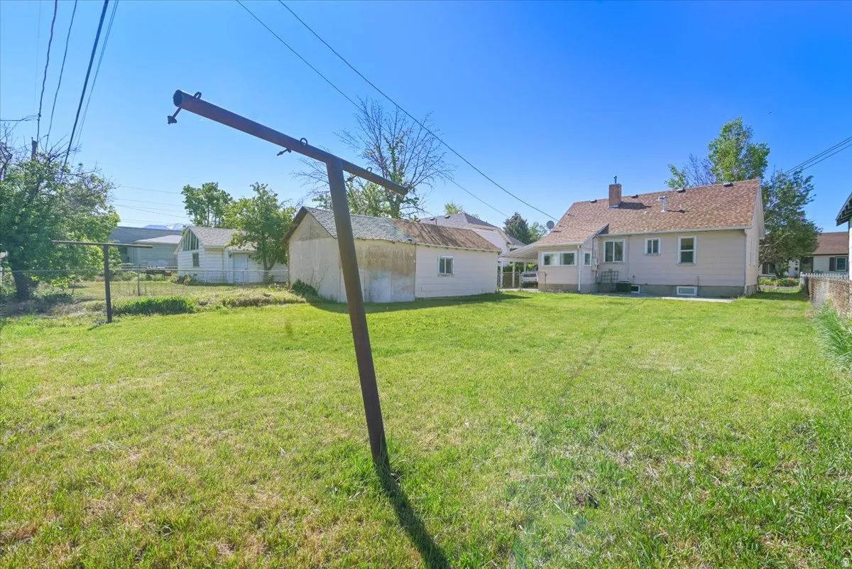 Expansive rear yard featuring a large grass area, a detached auxiliary building, and a paved patio area