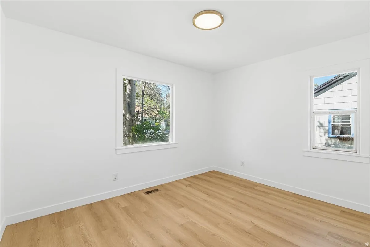 Light-filled interior featuring wood-finish flooring, crisp white walls, white baseboards, and a contemporary ceiling light fixture