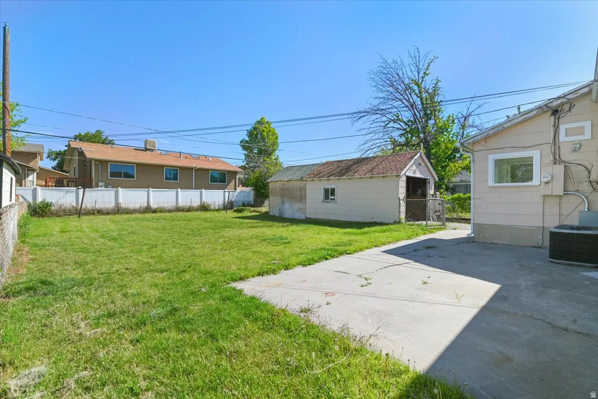 Expansive rear yard featuring a concrete pad, a detached storage building, and a chain-link fence
