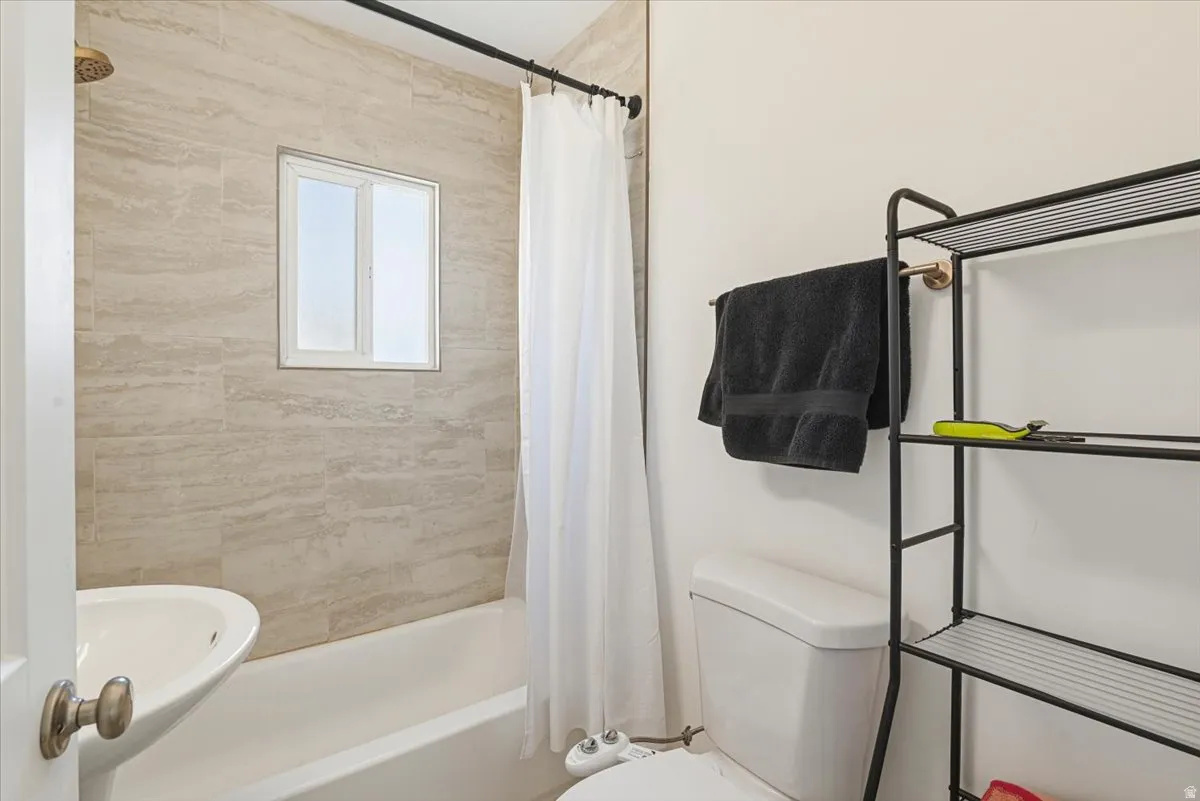 Bathroom featuring a white bathtub, pedestal sink, and toilet