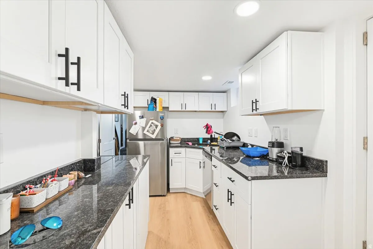Kitchen featuring white cabinetry, dark stone countertops, wood-finish flooring, and recessed ceiling lighting