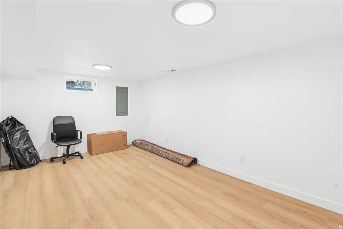 Spacious room with light wood-finish flooring, white walls, and recessed lighting