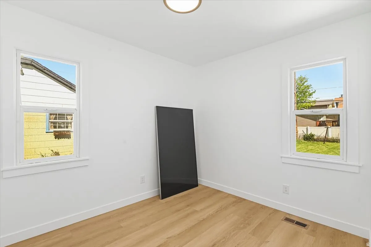 Bright room featuring wood-finish flooring, white walls, and two single-hung windows with white trim