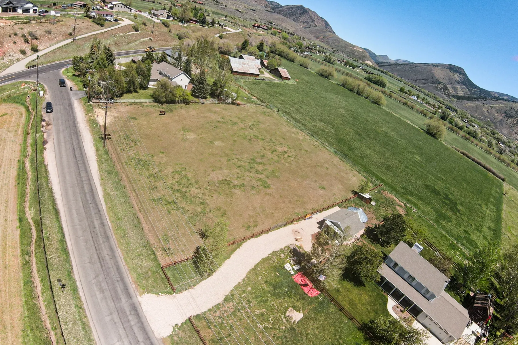 Expansive lot featuring a gravel driveway, mature trees, and mountainous surroundings