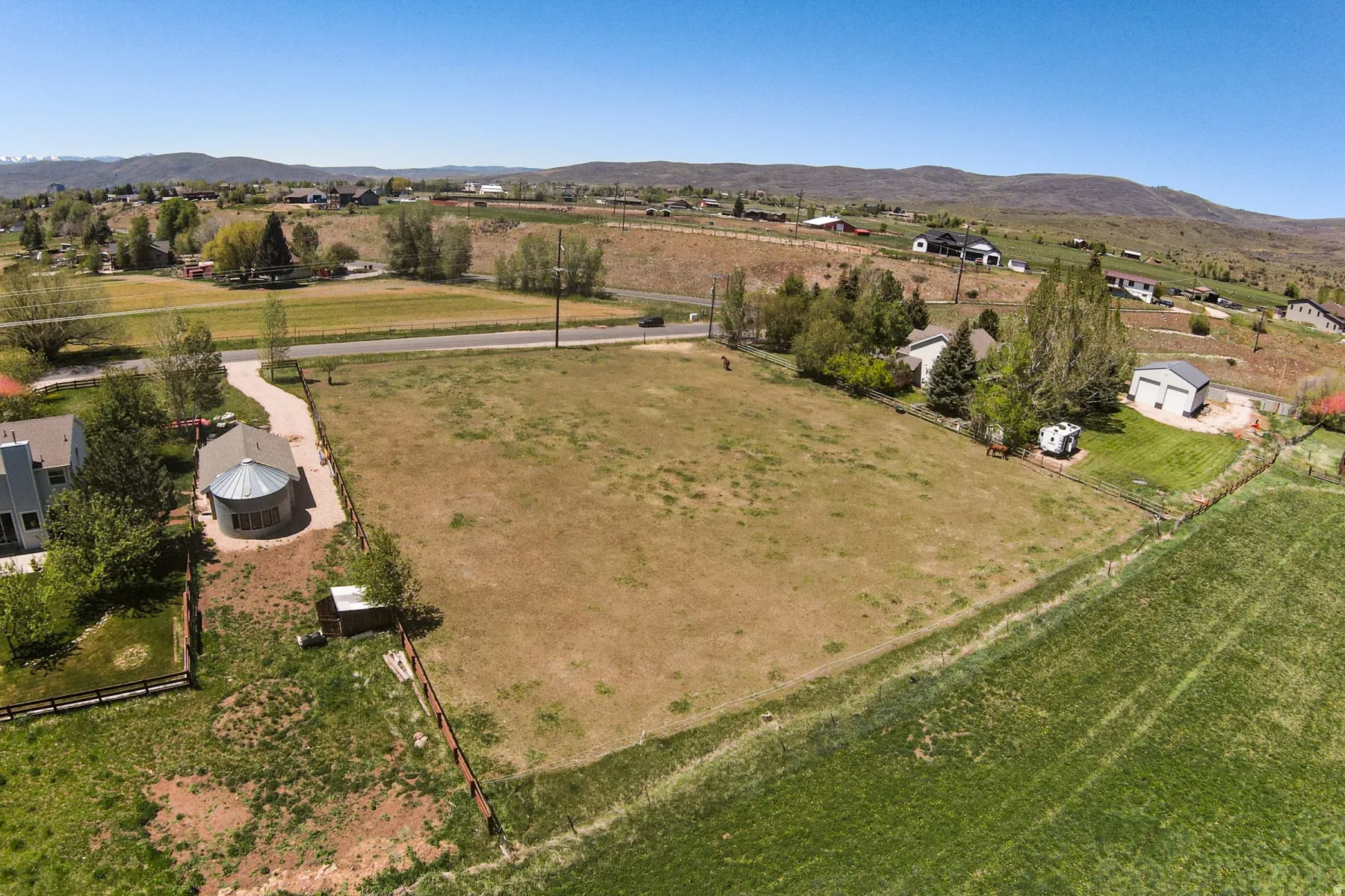 Expansive land parcel featuring open fields, distant mountain terrain, and established road access