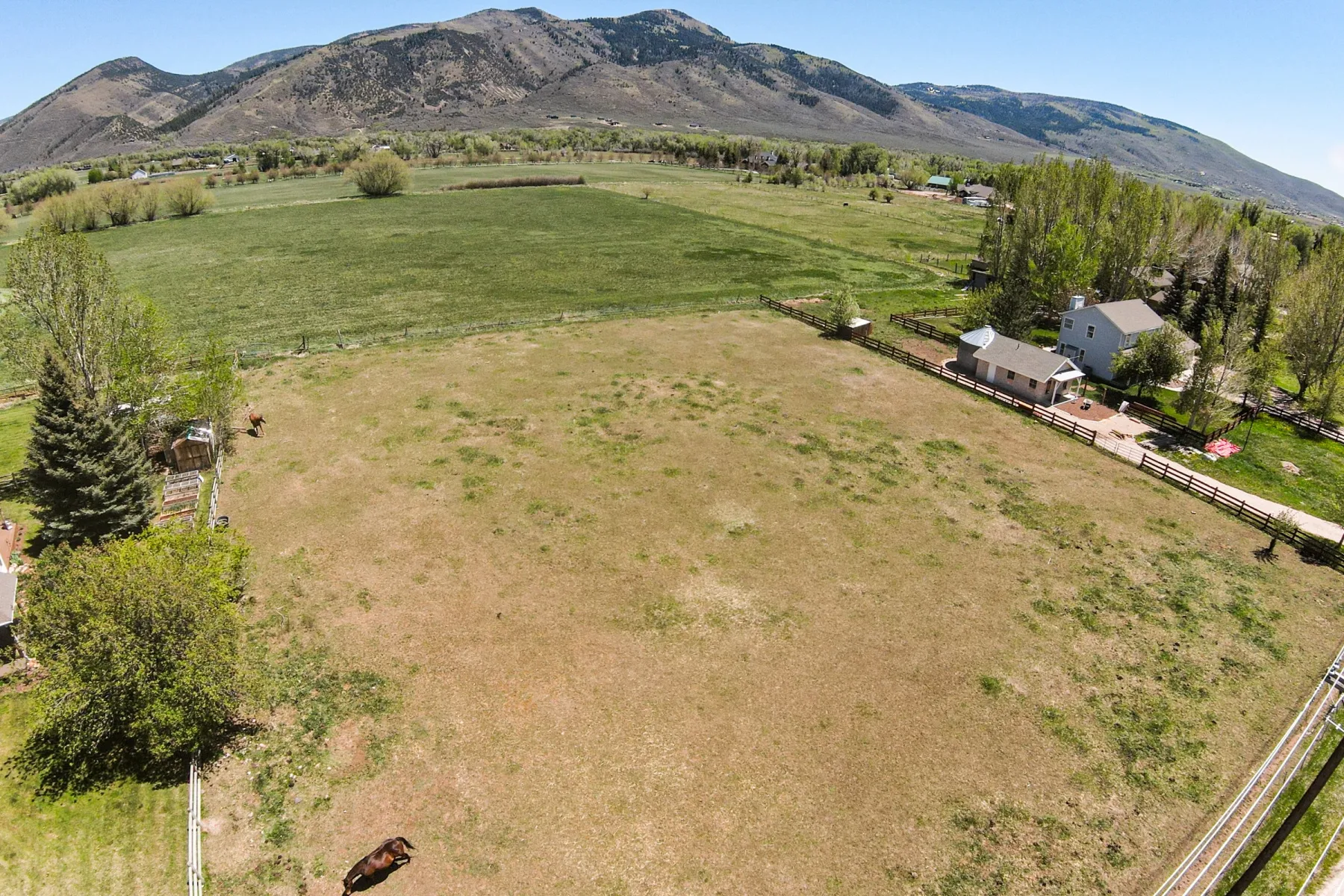 Expansive property featuring a large open field, perimeter fencing, and mature trees