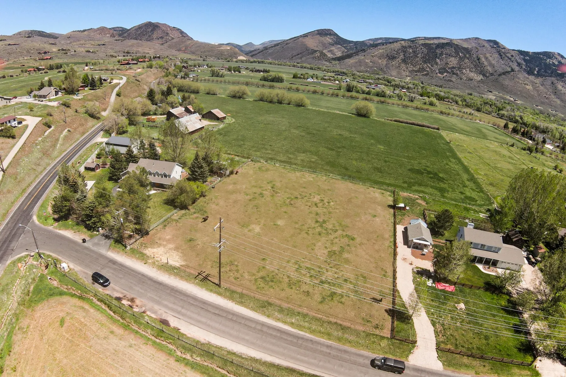 Expansive property featuring a large parcel of open land, paved road frontage, and a mountain backdrop