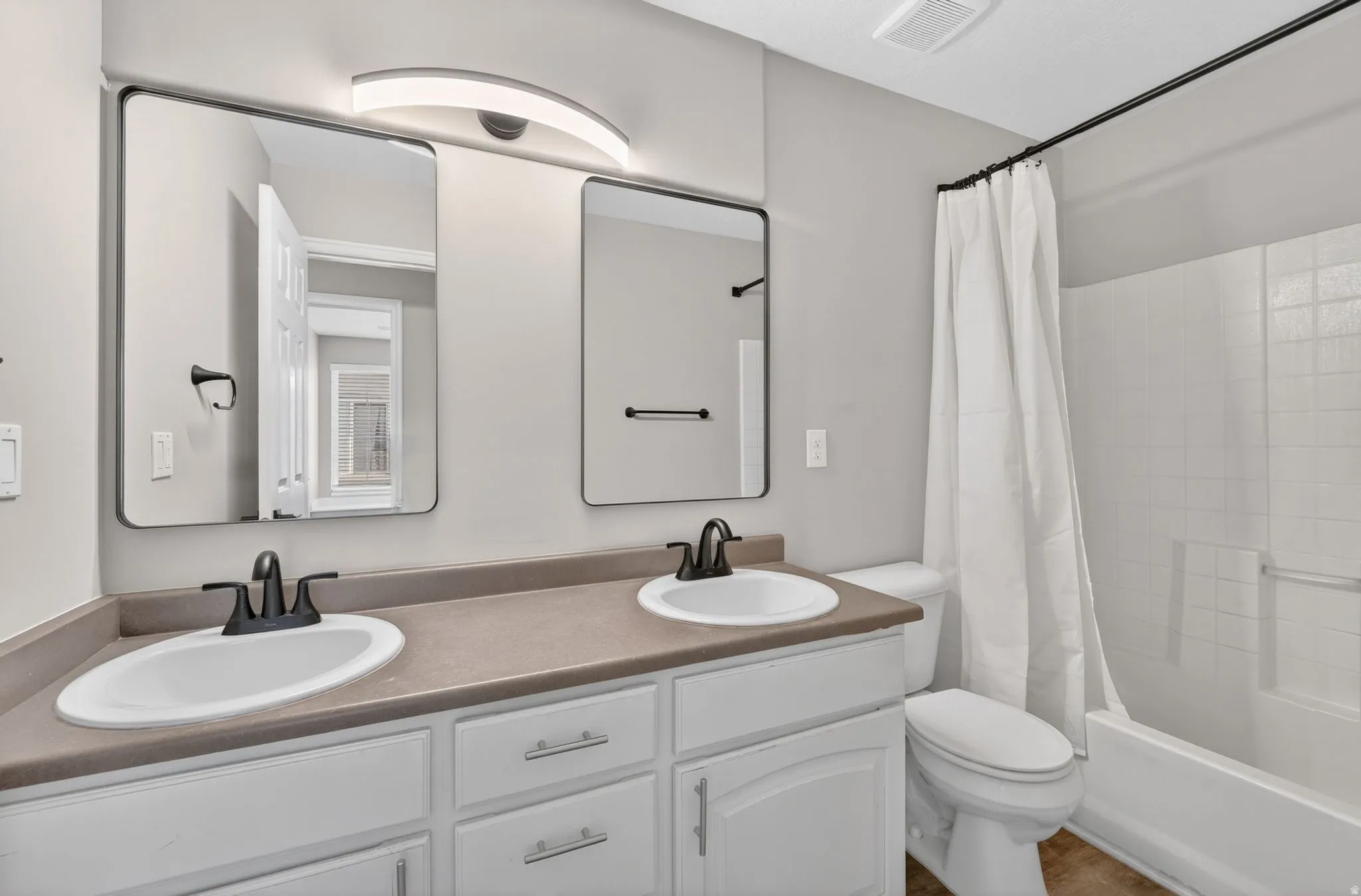 Bathroom featuring a dual vanity with white cabinetry and dark countertops