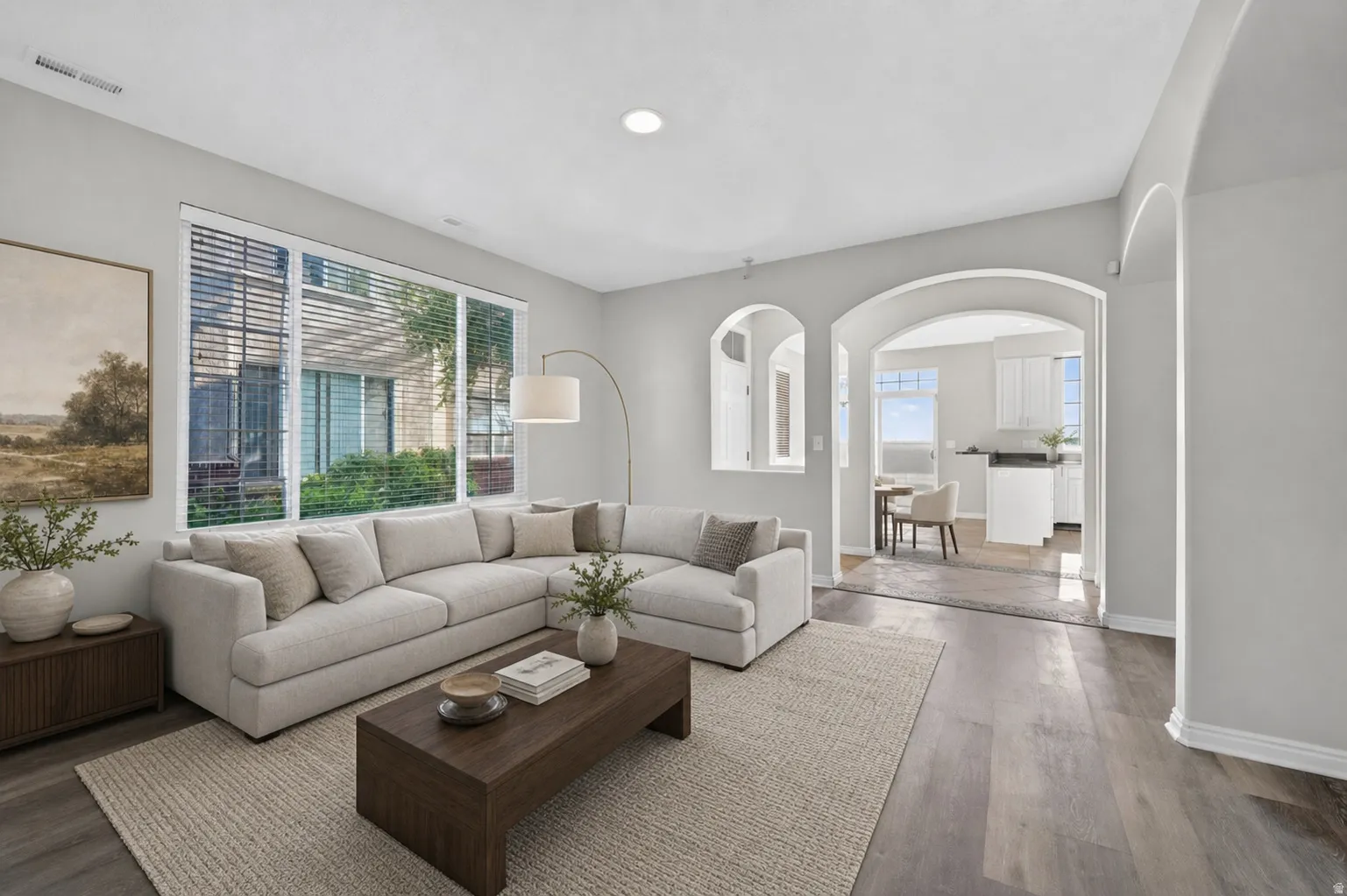 Spacious living area featuring wide plank wood-finish flooring, recessed lighting, and a large window with horizontal blinds