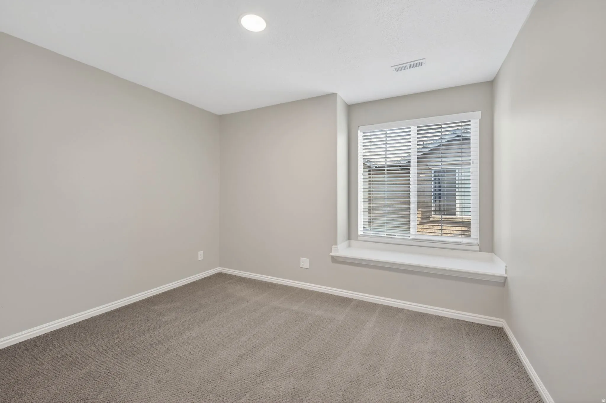 Carpeted room featuring a window with horizontal blinds and a window seat