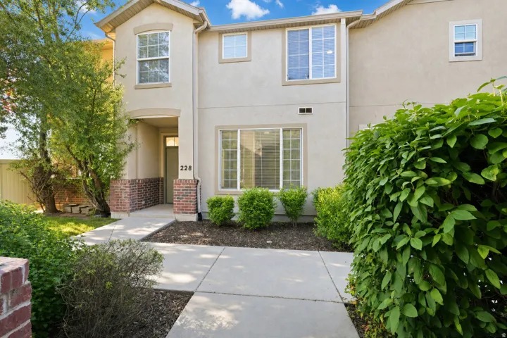 Stucco exterior featuring a covered entry with brick accents