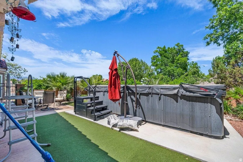 Outdoor spa with a cover, integrated steps, and an adjacent concrete patio