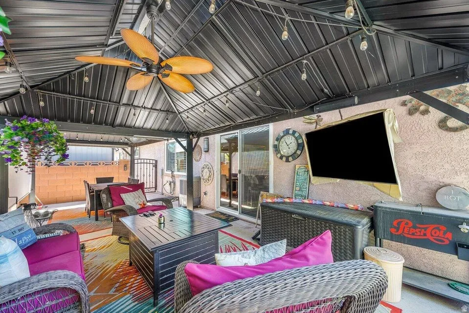 Covered patio space featuring a metal gazebo roof with an integrated ceiling fan and string lighting