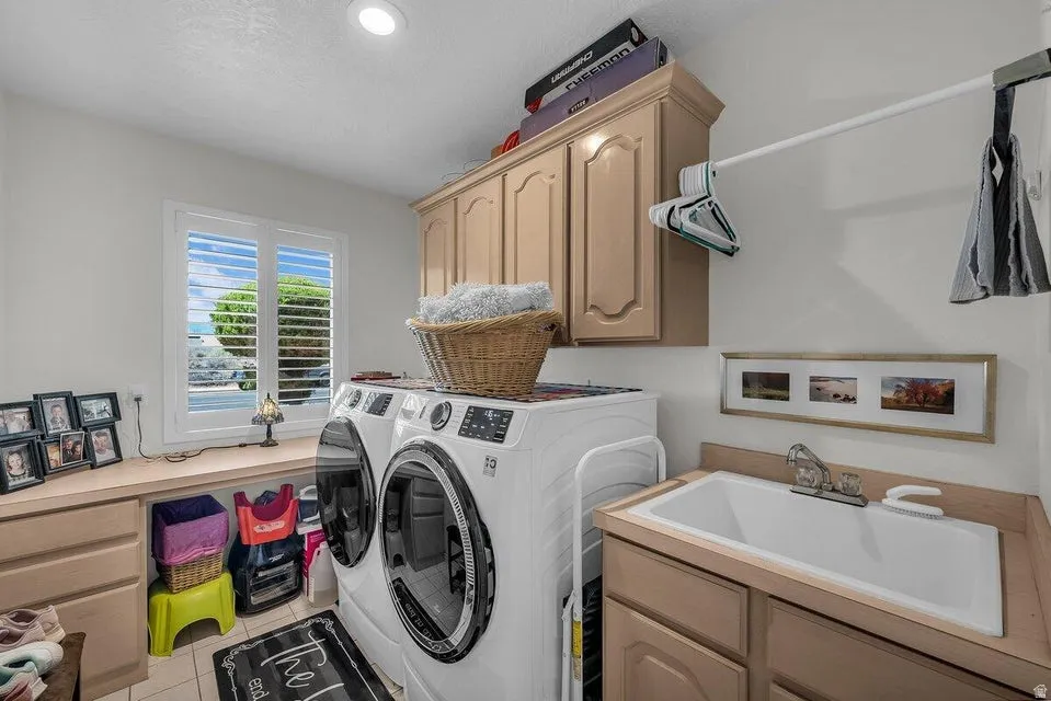 Utility room featuring a window with plantation shutters, upper cabinetry, a built-in sink with countertop space, and a wall-mounted drying rod