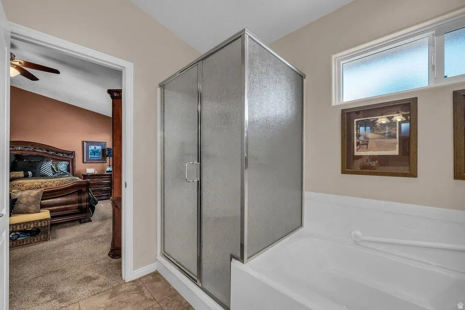 Frosted glass shower enclosure, a full-size bathtub, and tile flooring
