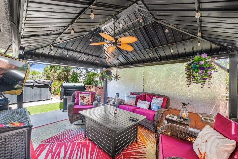 Covered patio with a dark metal roof, string lighting, and a ceiling fan