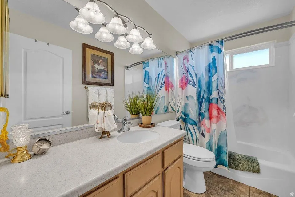 Full bathroom featuring a single vanity with a light-toned countertop, wood-finish cabinetry, a built-in bathtub with shower, and an overhead window
