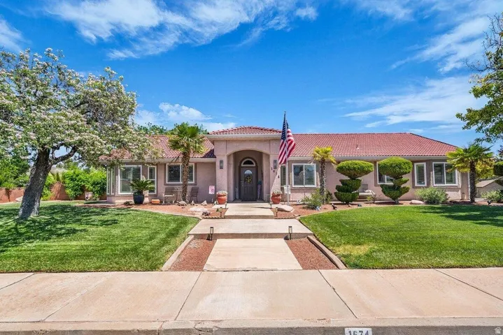 Southwest-style residence featuring a red tile roof, stucco exterior, and a grand arched entryway