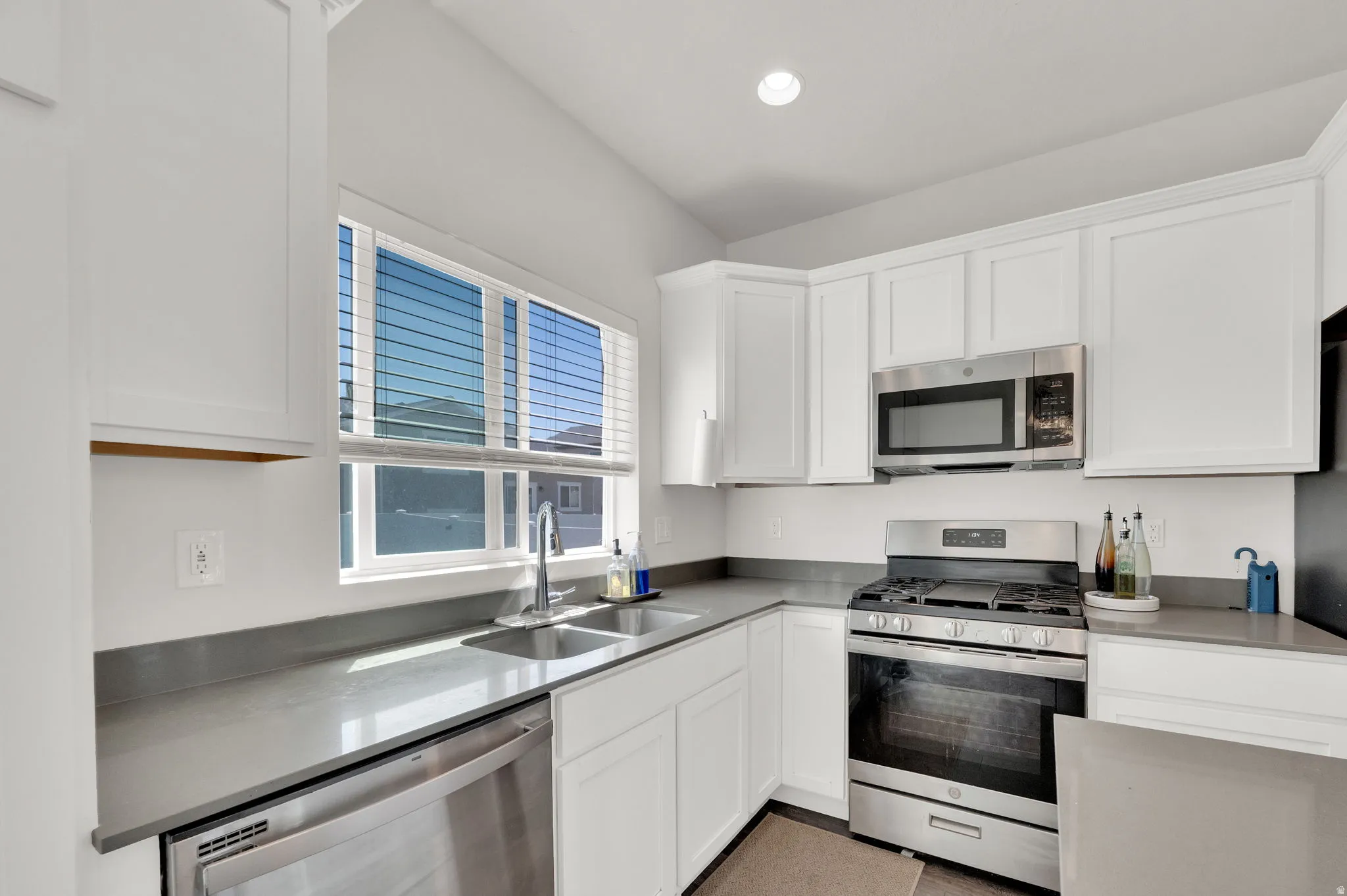 Modern kitchen with white cabinetry, stainless steel appliances and grey quartz countertops