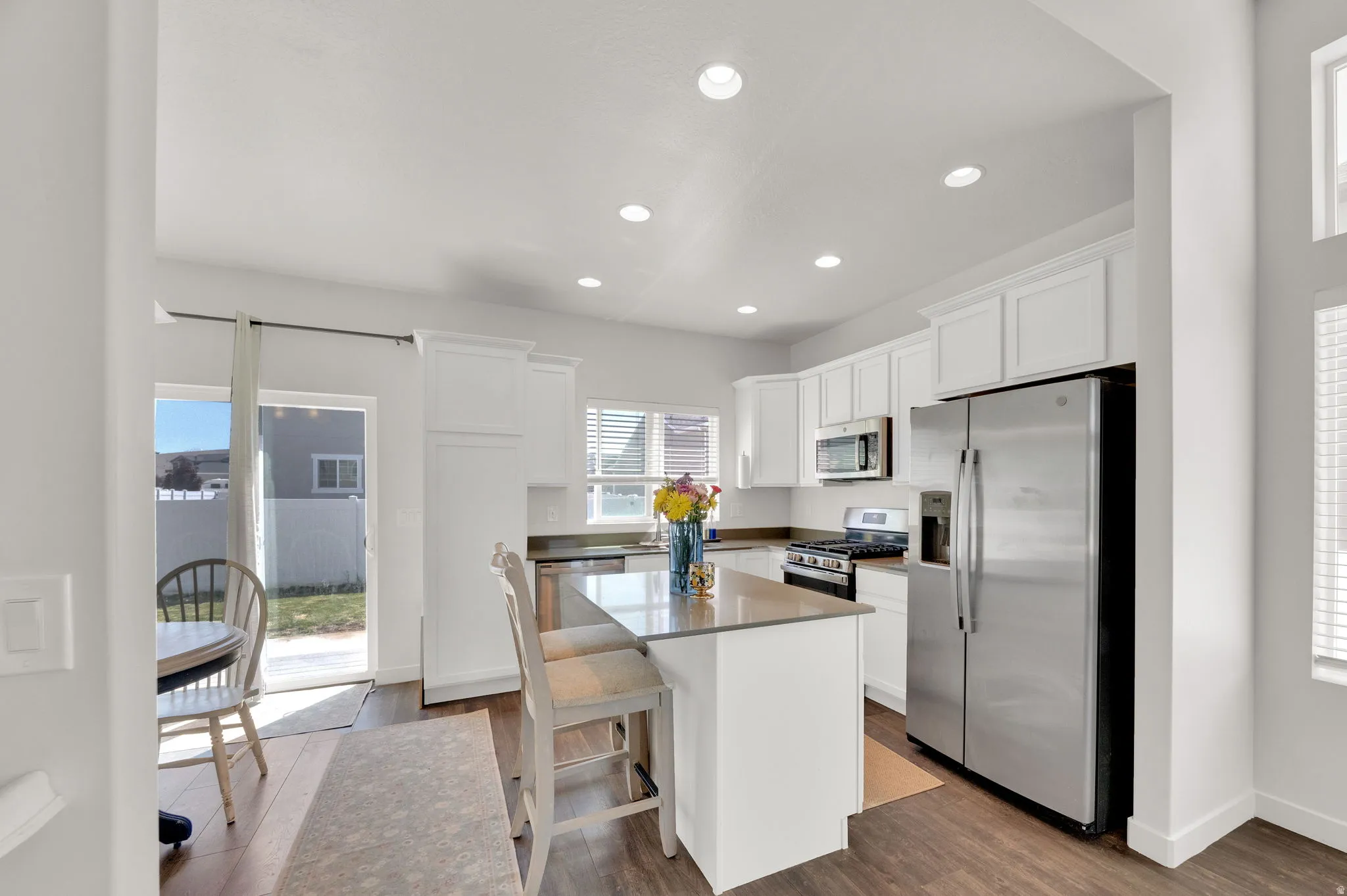 Contemporary kitchen featuring white cabinetry, stainless steel appliances, an island with countertop seating, recessed lighting, and wood-finish flooring