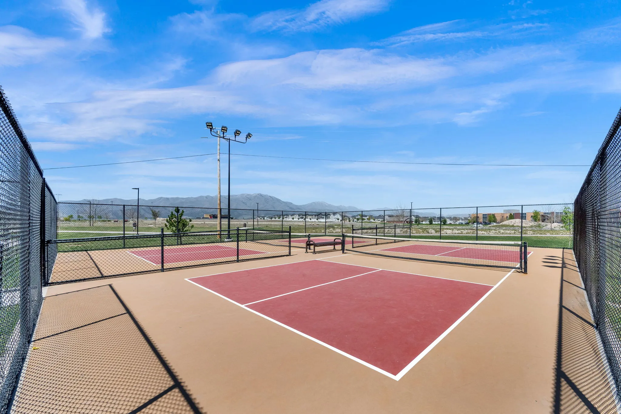 Pickleball courts featuring a durable playing surface, perimeter chain-link fencing, and overhead lighting