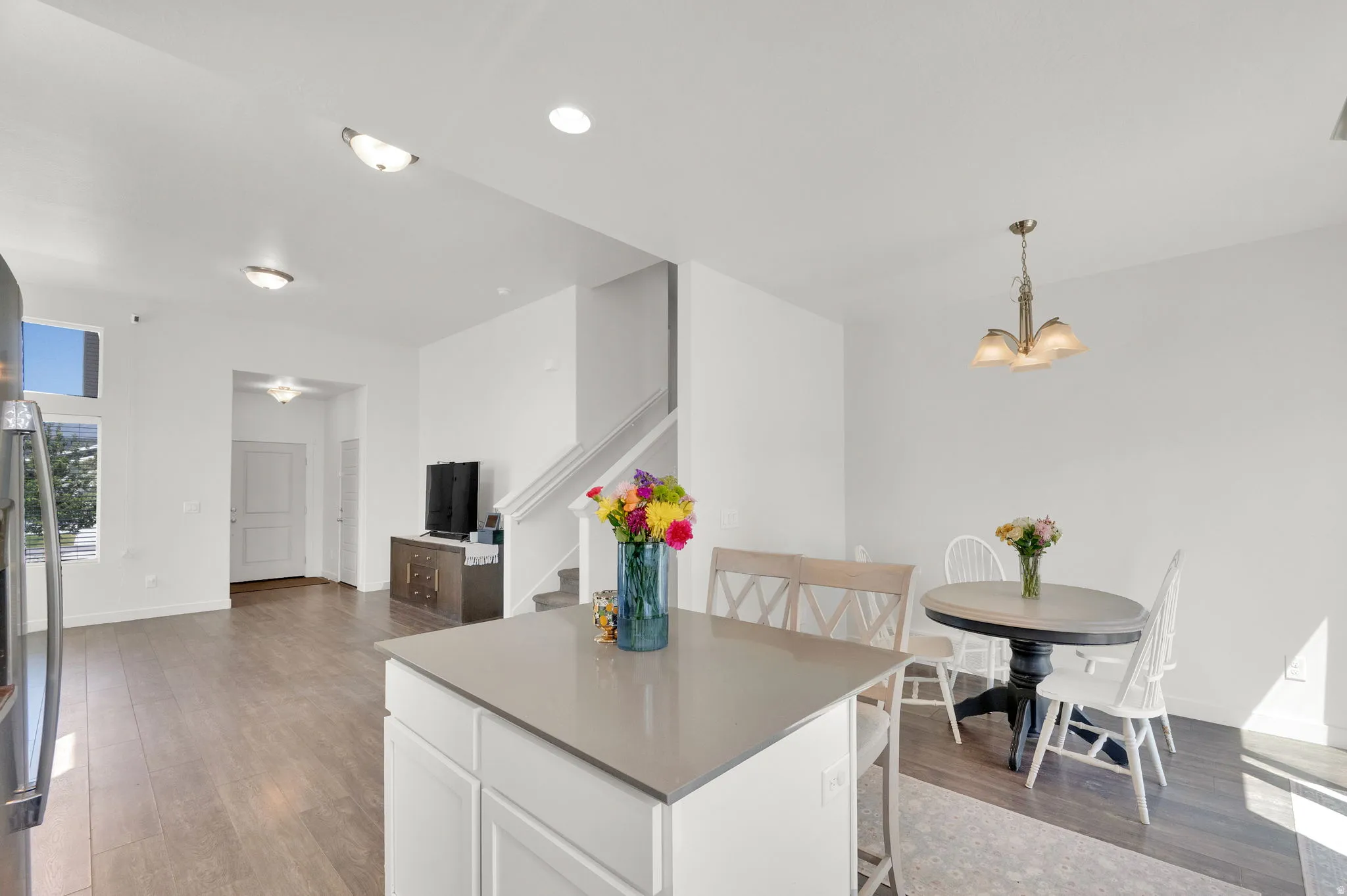 Open-concept living space with wood-finish flooring, a kitchen island with a light-toned countertop, and recessed lighting