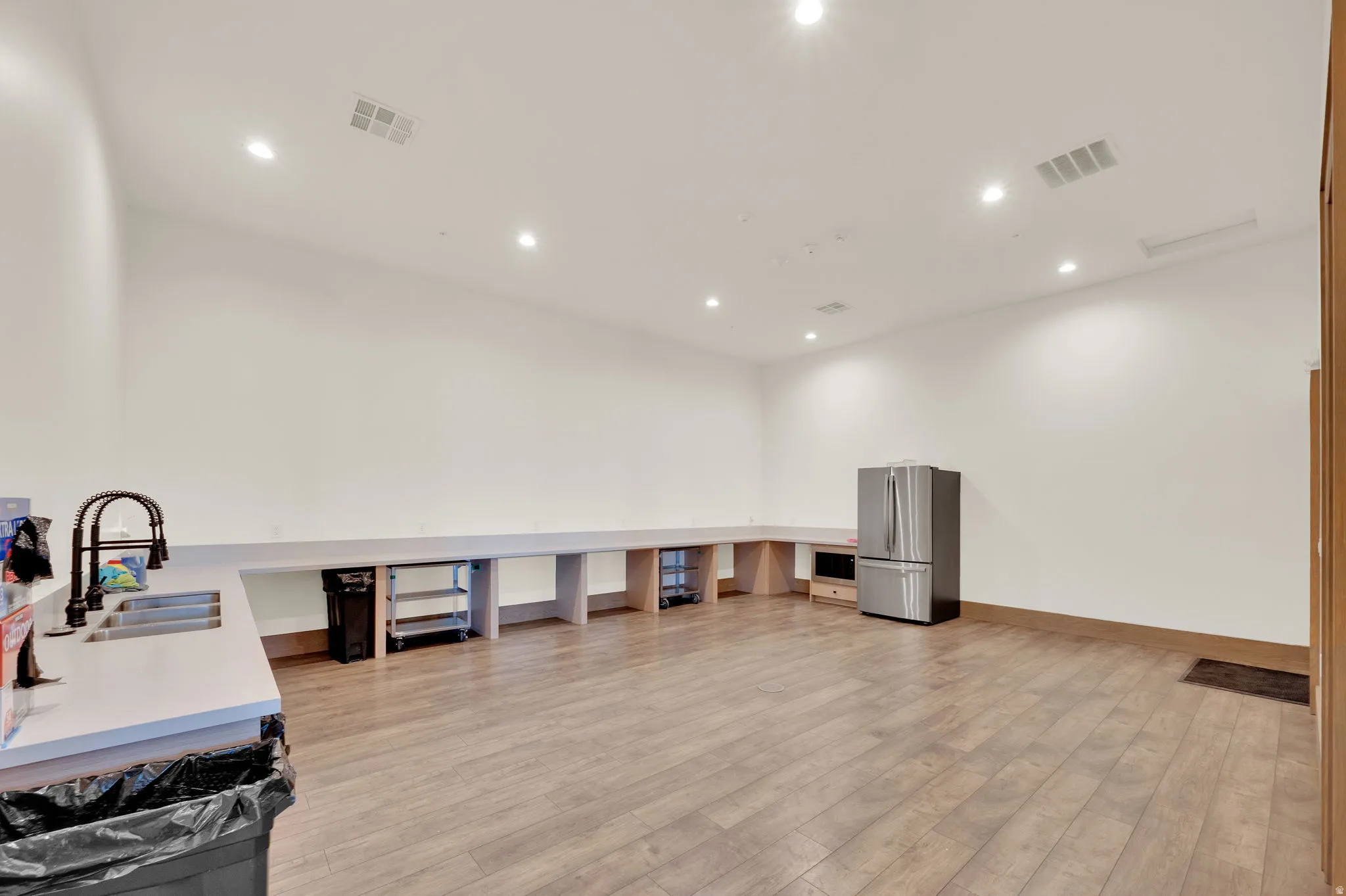 Spacious room featuring wood-finish flooring, recessed lighting, and white walls