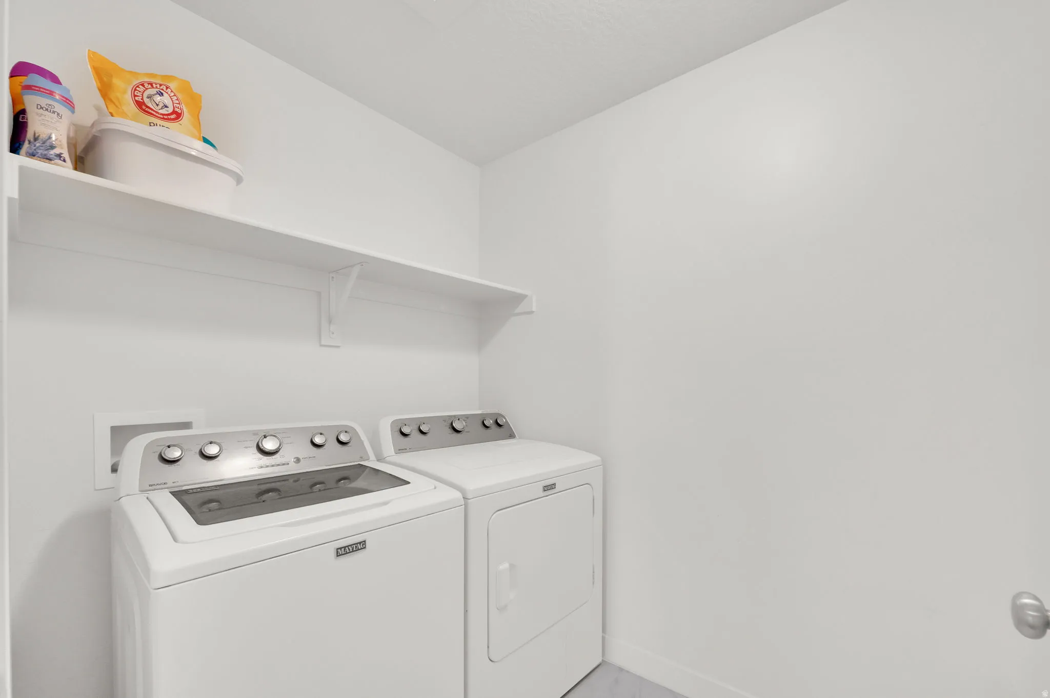 Dedicated laundry area featuring white walls and a white built-in shelf