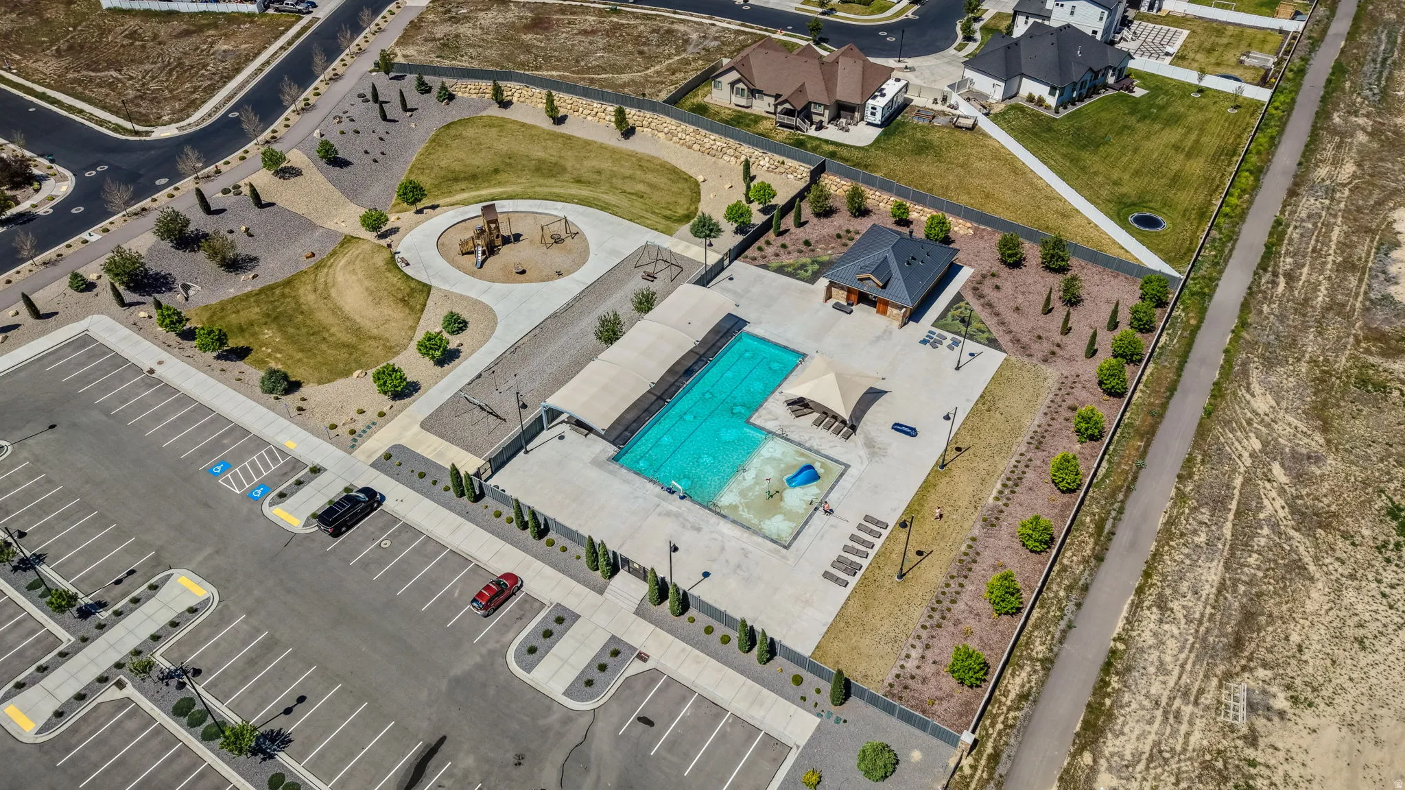Community recreation area featuring a large swimming pool, separate children's splash pad, and a shaded pergola