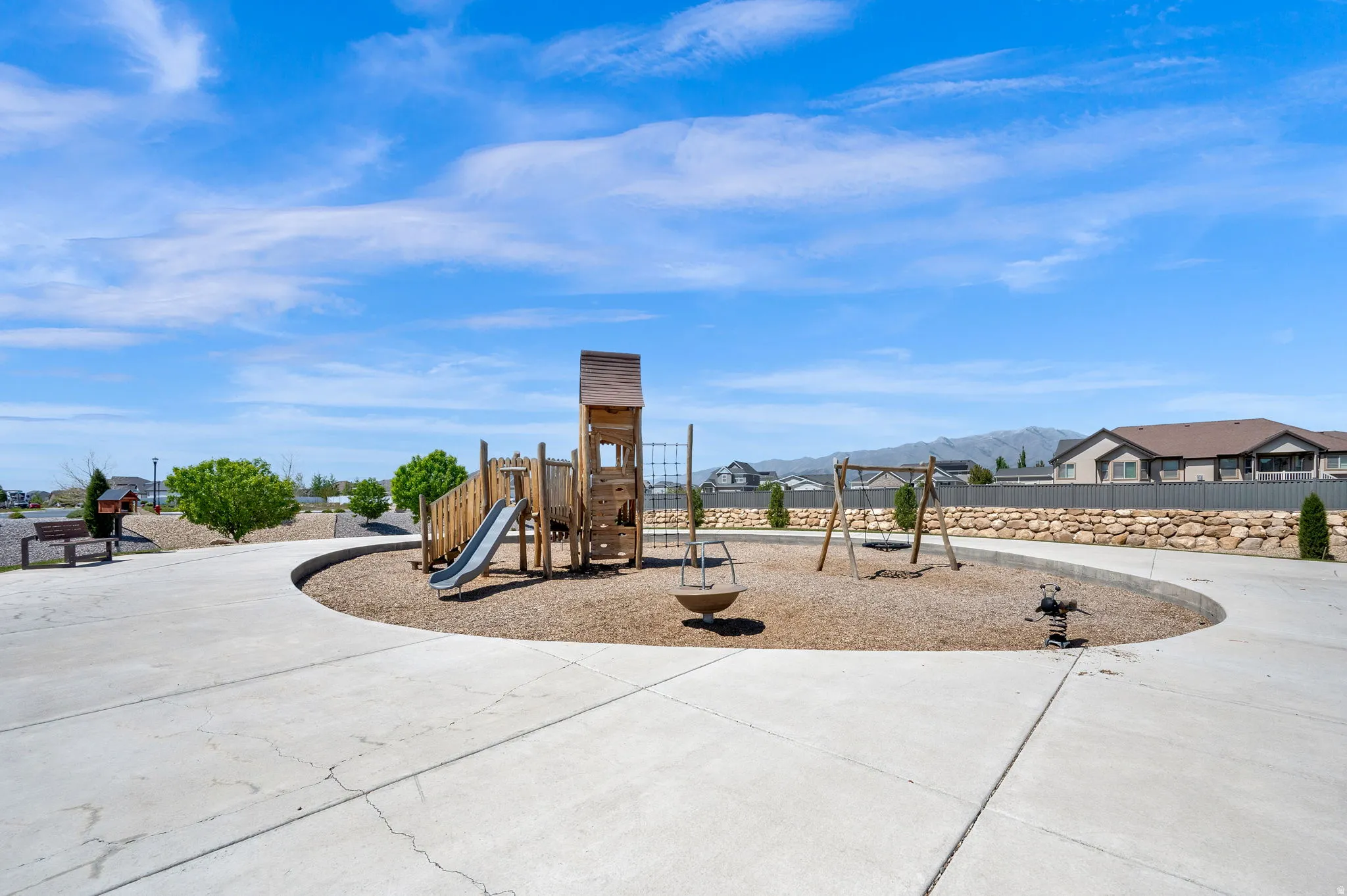 Community park featuring a play structure with a slide, swing set, and spring rider