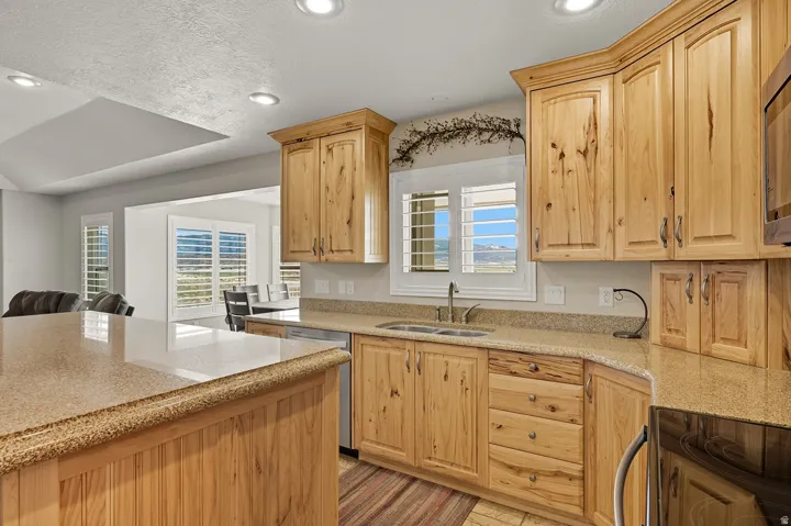 Kitchen featuring natural wood cabinetry, light-toned countertops, a stainless steel sink, recessed lighting, and a kitchen island with beadboard paneling