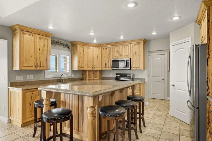 Kitchen featuring natural wood cabinetry, recessed lighting, and a large central island with seating