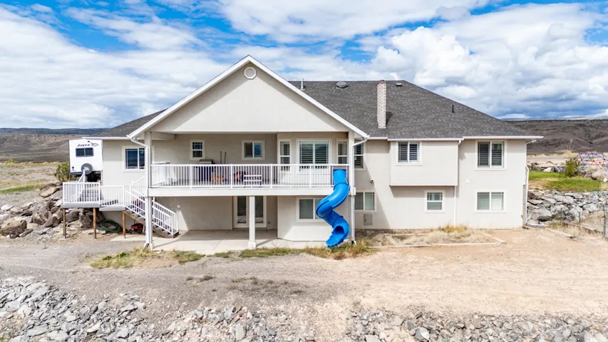 Rear exterior featuring a multi-level deck, lower patio area, and a spiral slide