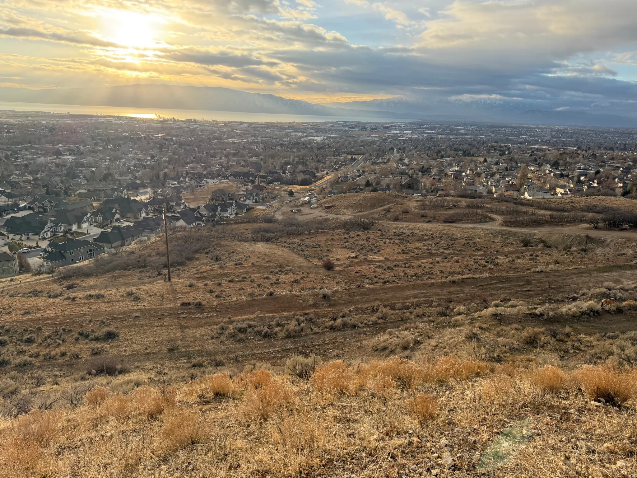 Expansive hillside property featuring distant water, mountains, and a suburban landscape