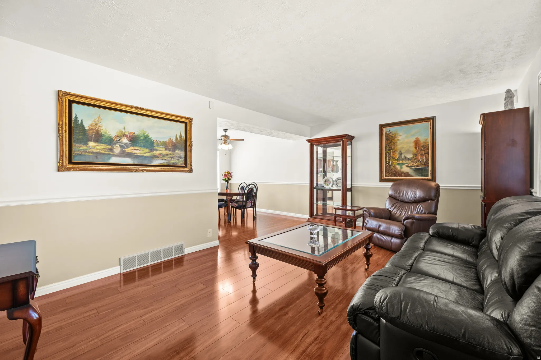 Living area featuring wood-finish flooring, two-tone wall treatment, and an open doorway to another room