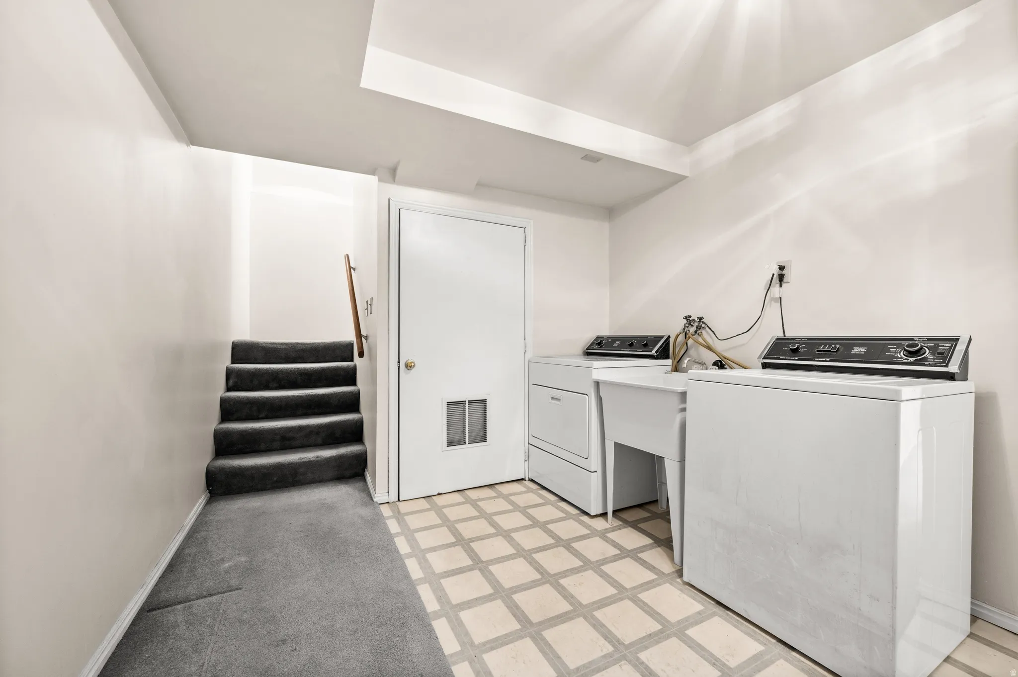 Dedicated laundry area featuring a utility sink and patterned floor tiling