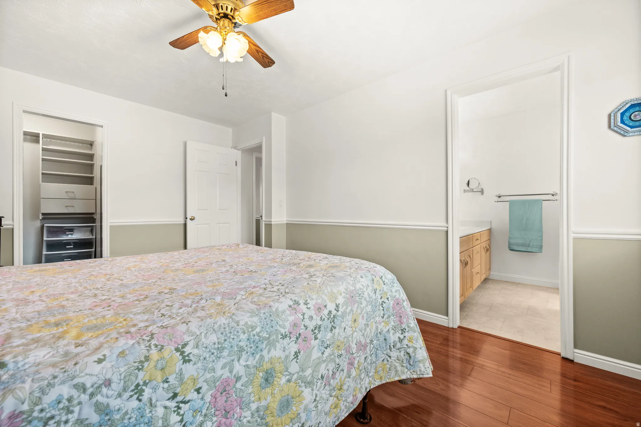 Hardwood-finish flooring enhancing a room with a ceiling fan, crown molding, and two-tone wall paneling